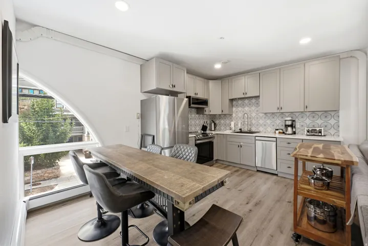 Kitchen featuring stainless steel appliances, light gray cabinetry, and a patterned tile backsplash