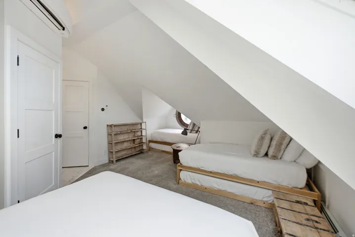 Carpeted attic space featuring sloped ceilings, white paneled doors, and a round window