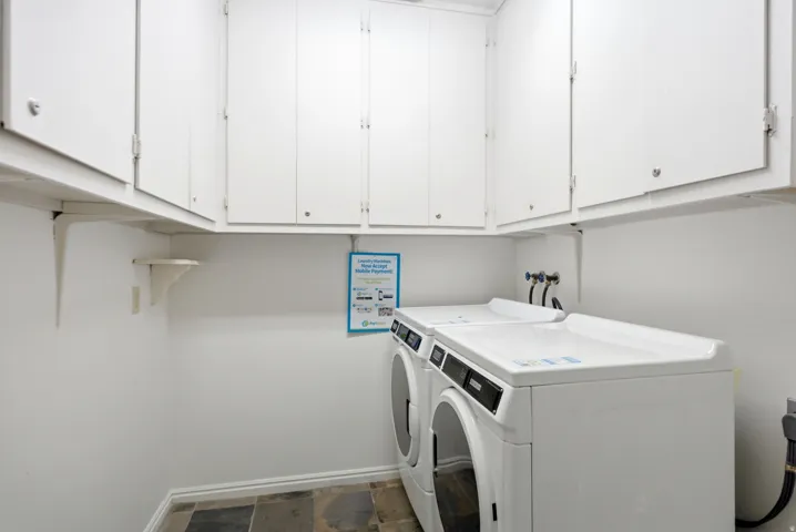 Dedicated laundry area featuring white upper cabinetry, tiled flooring, and white walls