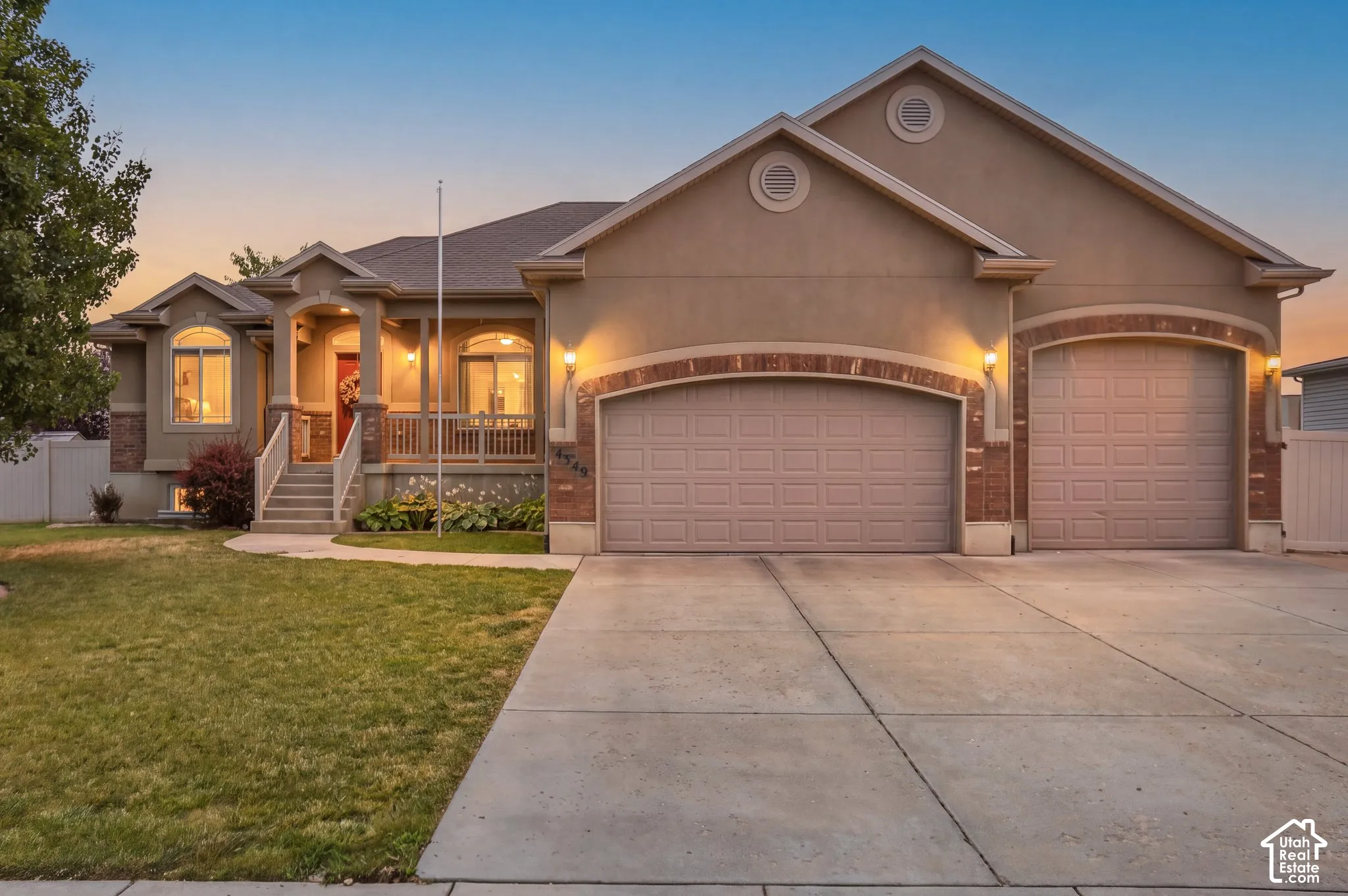 Single-story exterior featuring stucco and brick siding, a covered front porch, arched entryway detailing, and a three-car garage