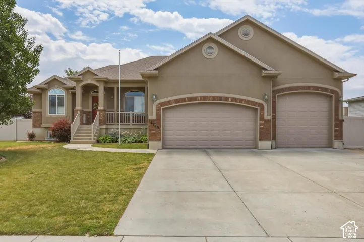 Stucco exterior featuring brick accents, a covered front porch, and a concrete driveway