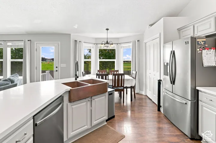 Bright, open kitchen featuring white cabinetry, stainless steel appliances including a French-door refrigerator, and copper farmhouse sink