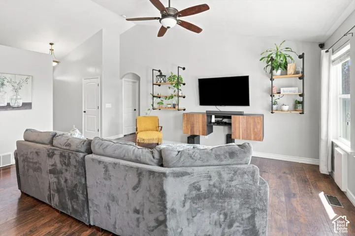 Living area featuring LVP flooring, vaulted ceilings, a ceiling fan, and built-in shelving