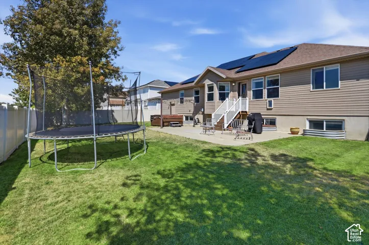 Expansive backyard oasis featuring a manicured lawn, mature shade trees, and a patio
