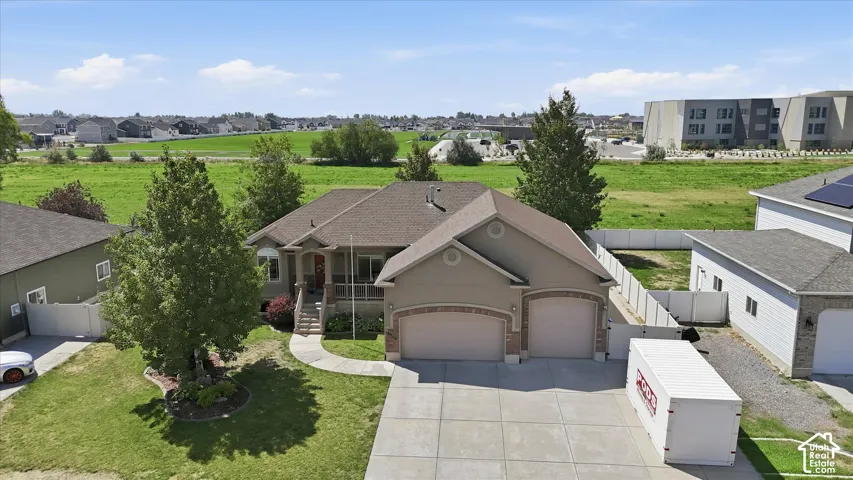 Stunning rambler featuring a prominent four-car garage with taupe exterior finish, pitched roofline with dimensional shingles, and mature landscaping with established trees framing the property