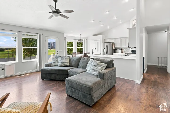 Open-concept living space featuring LVP flooring, vaulted ceilings with recessed lighting, and a ceiling fan