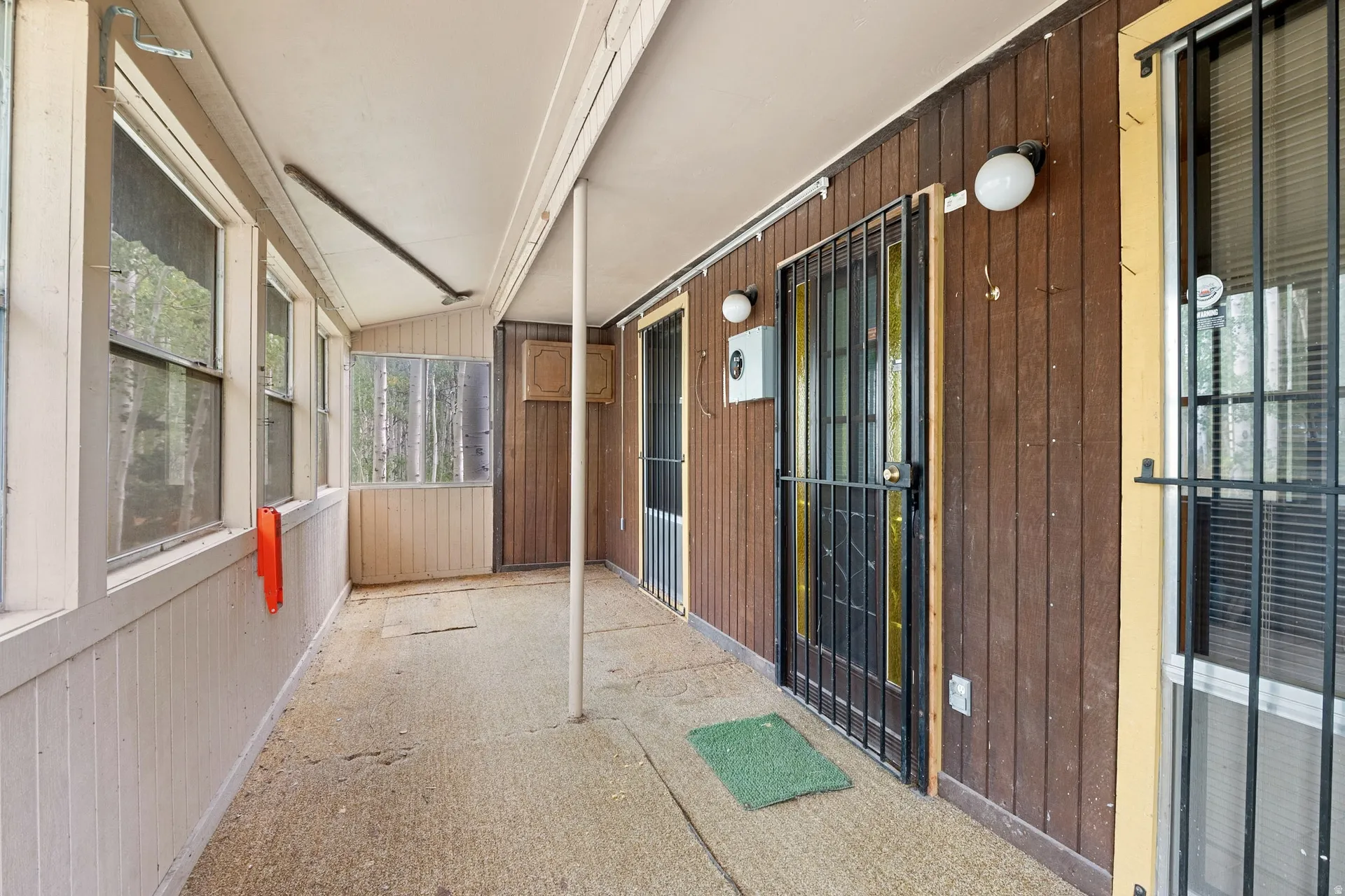 Screened porch with concrete flooring and wood-paneled walls