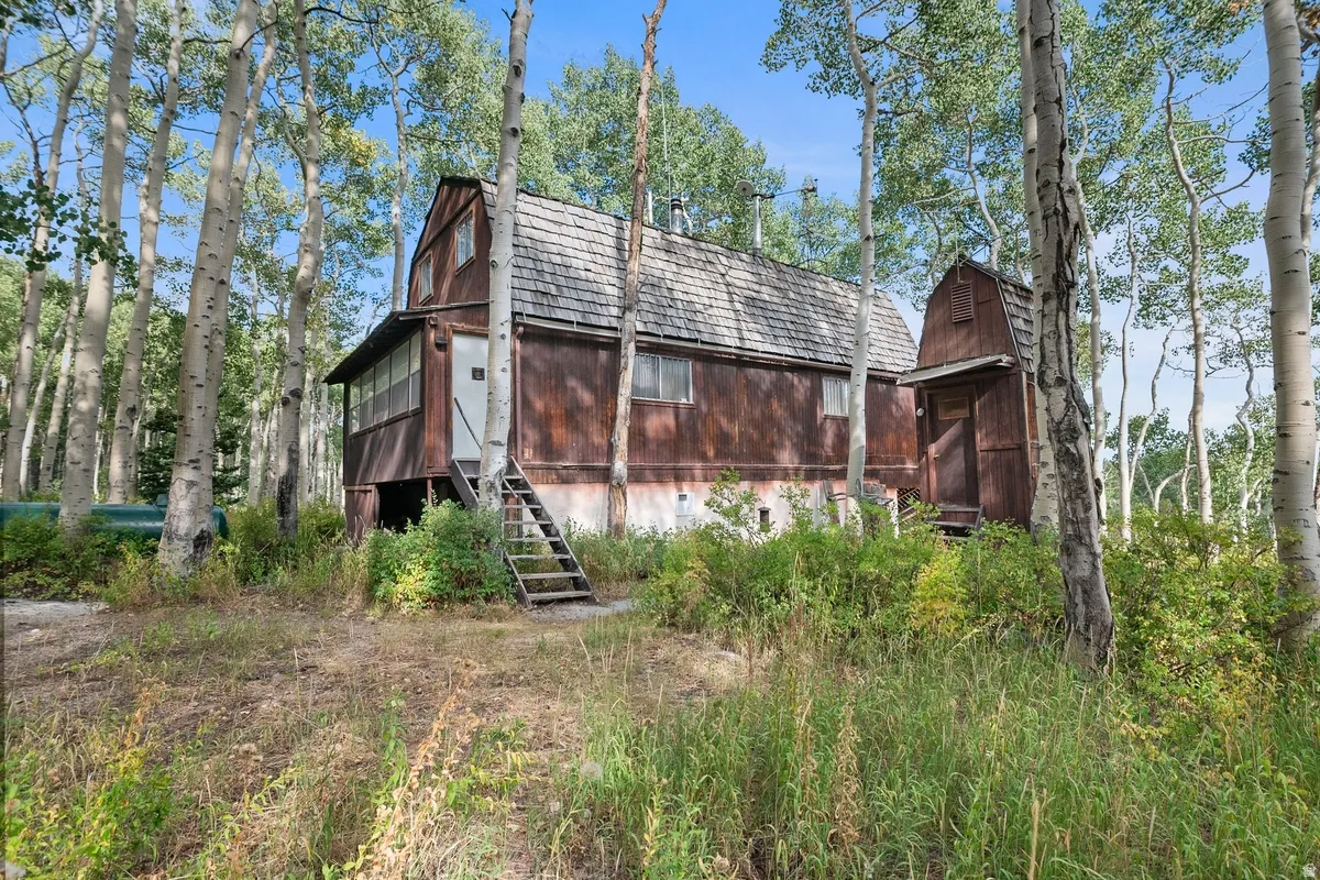 Wood-sided cabin featuring a shingled roof and an elevated screened porch