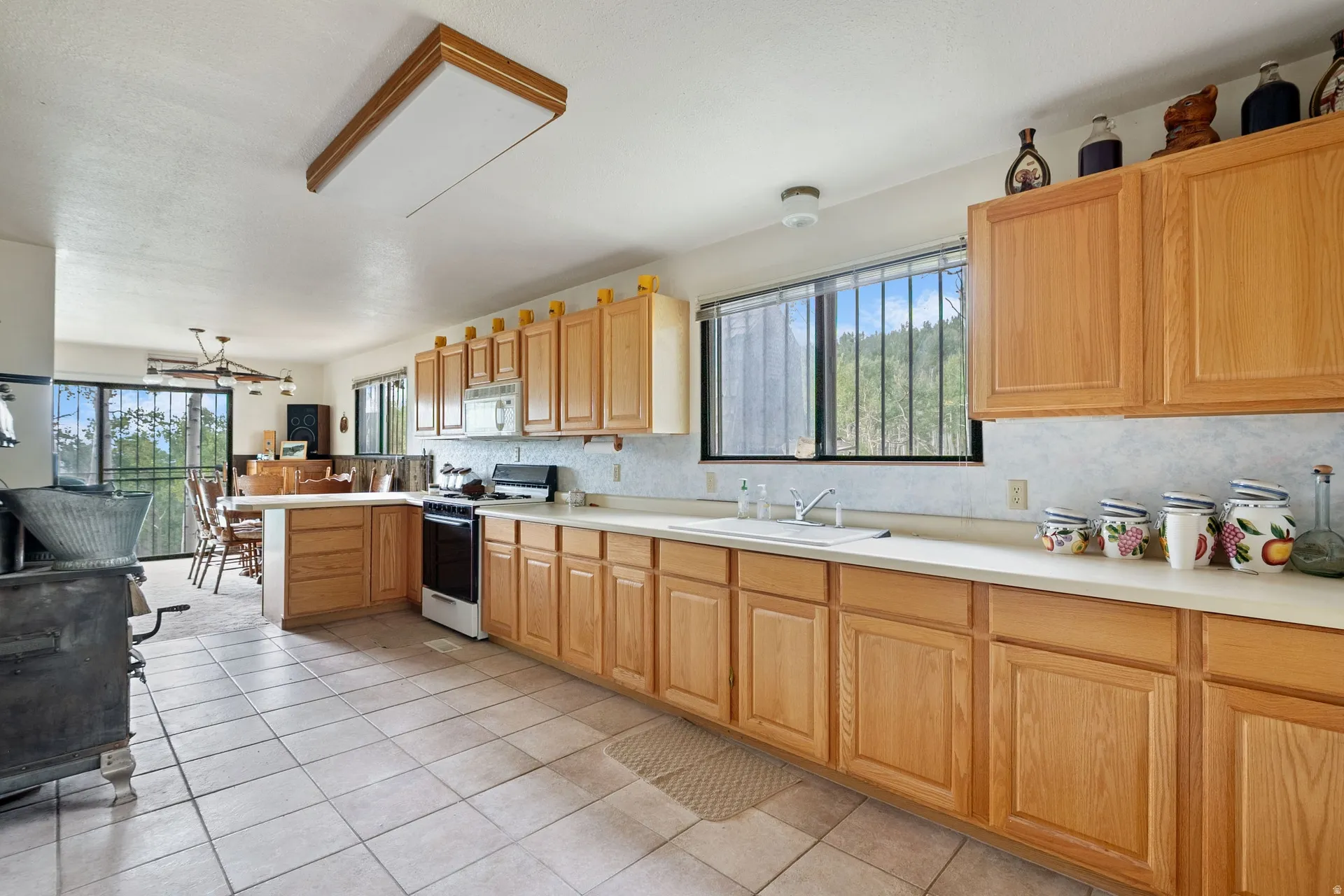 Open-concept kitchen with light wood cabinetry, a built-in oven, and a double basin sink