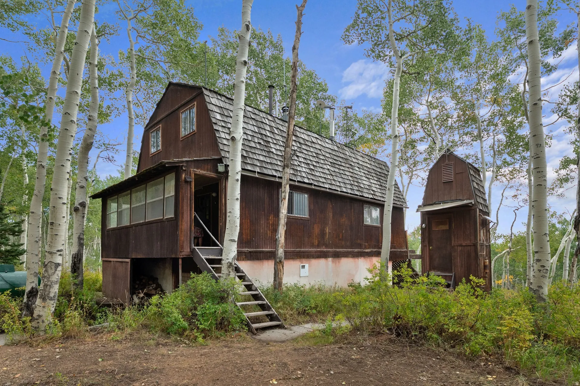 Rustic gambrel-roof residence featuring wood siding and a covered porch
