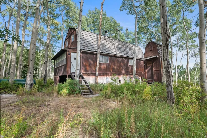 Wood-sided cabin featuring a shingled roof and an elevated screened porch