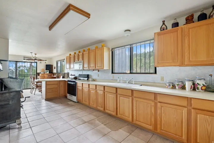 Open-concept kitchen with light wood cabinetry, a built-in oven, and a double basin sink