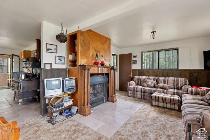 Living area featuring a prominent wood-clad fireplace surround with built-in shelving, wood-panel wainscoting, and large windows