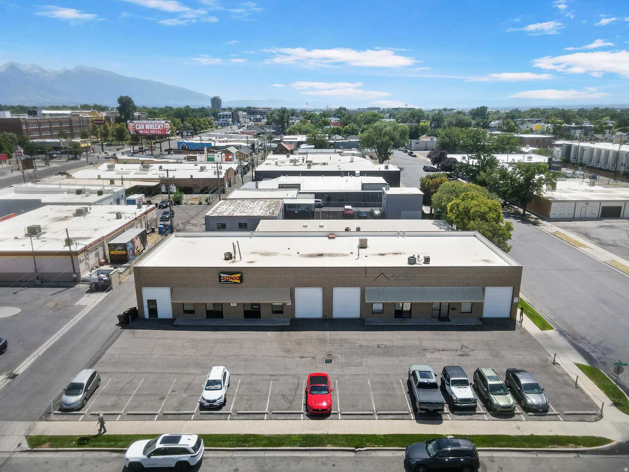 Modern commercial/industrial building featuring a clean, flat roof design with contemporary facade elements, ample front-facing parking with multiple marked spaces, and a functional layout ideal for retail or warehouse operations
