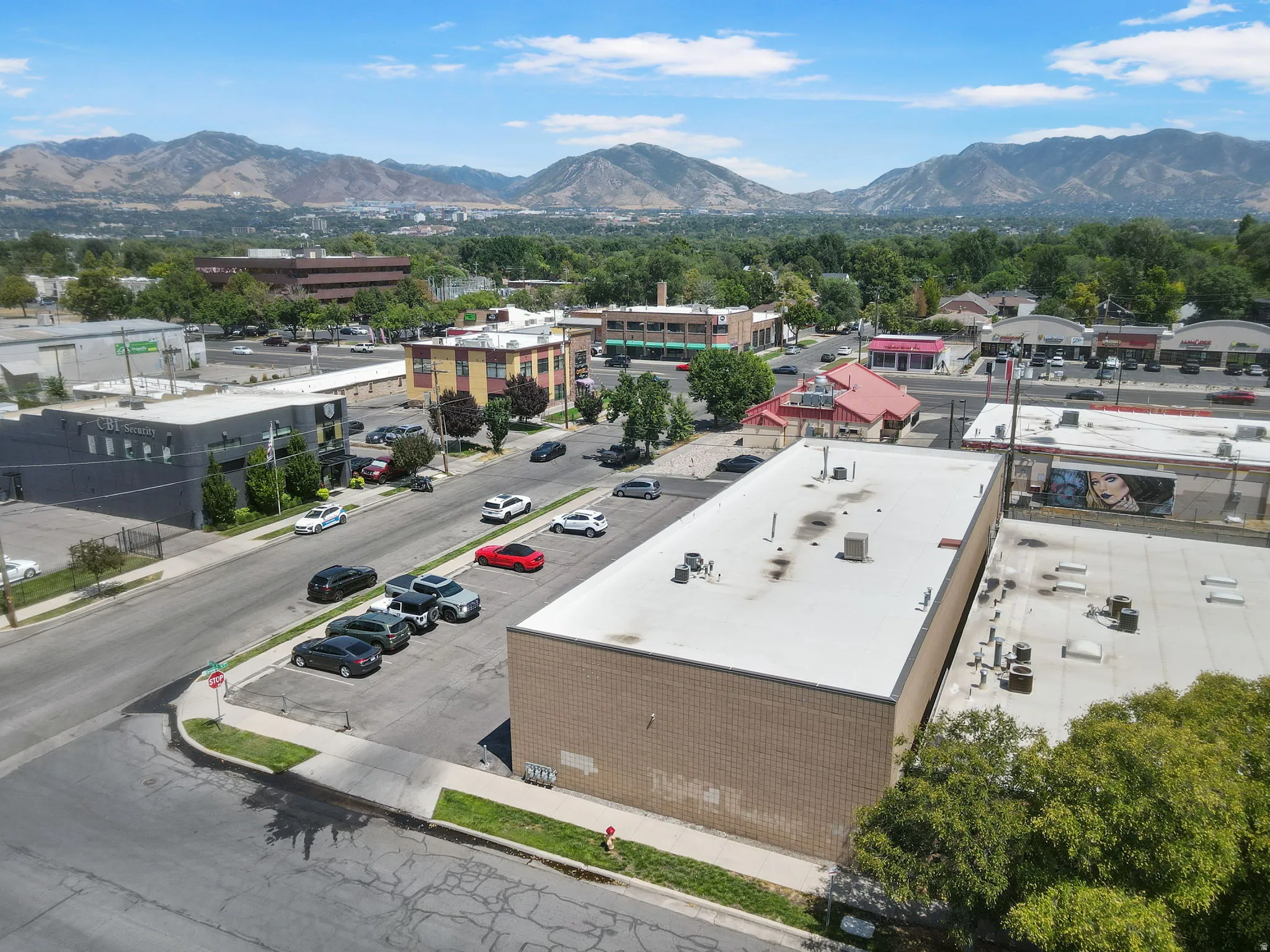 Industrial-style commercial building featuring a flat roof with mechanical systems, clean brick and metal exterior cladding, and ample front parking with striped spaces