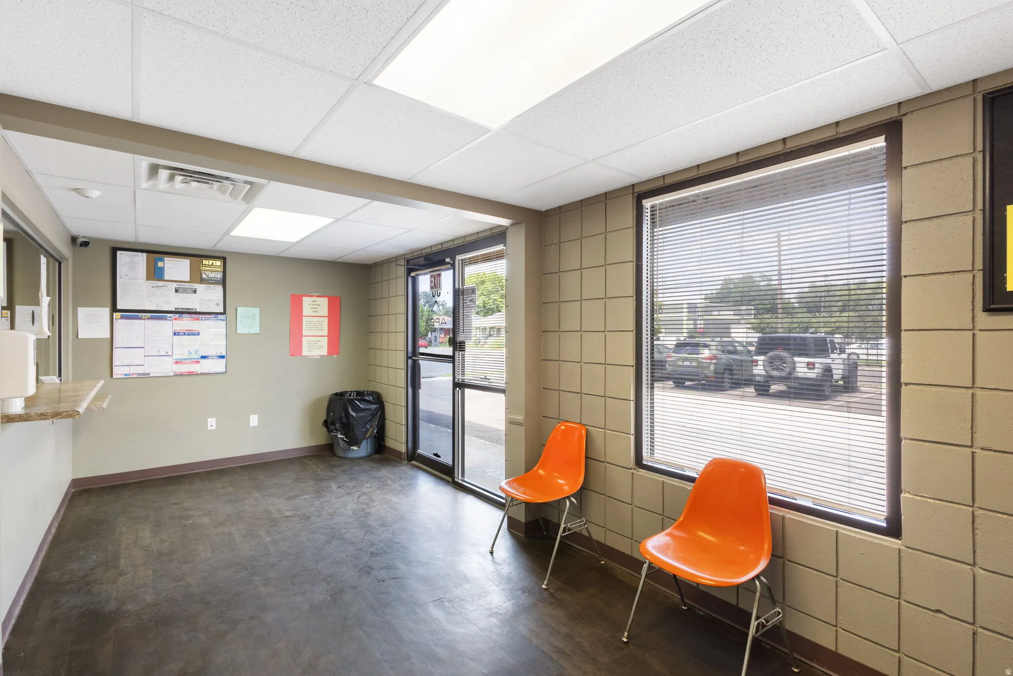 Reception area featuring a glass entry door, large window with blinds, drop ceiling with recessed lighting, and a built-in counter