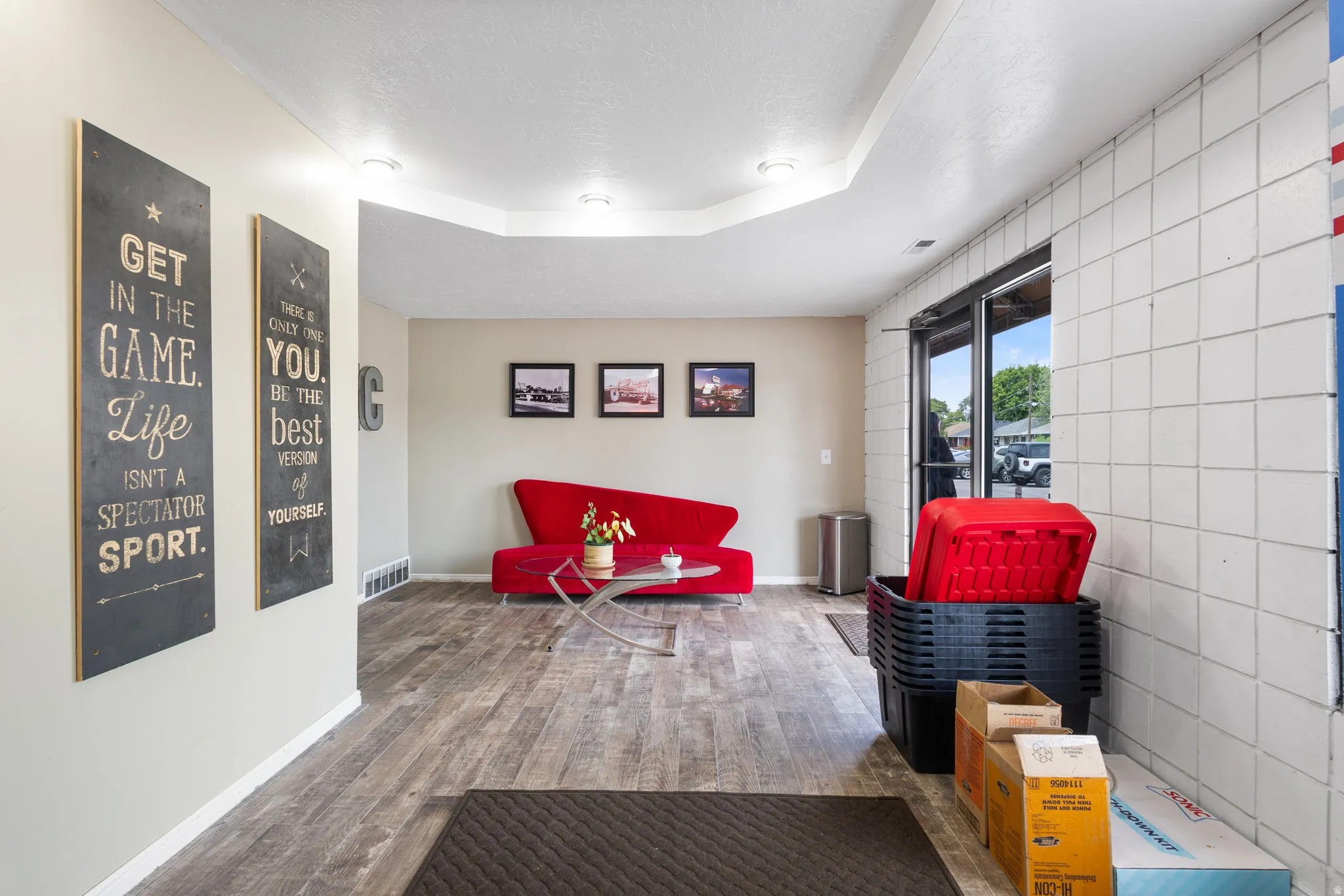 Modern recreational space featuring polished wood-finish flooring, recessed ceiling lighting, and white tile accent wall