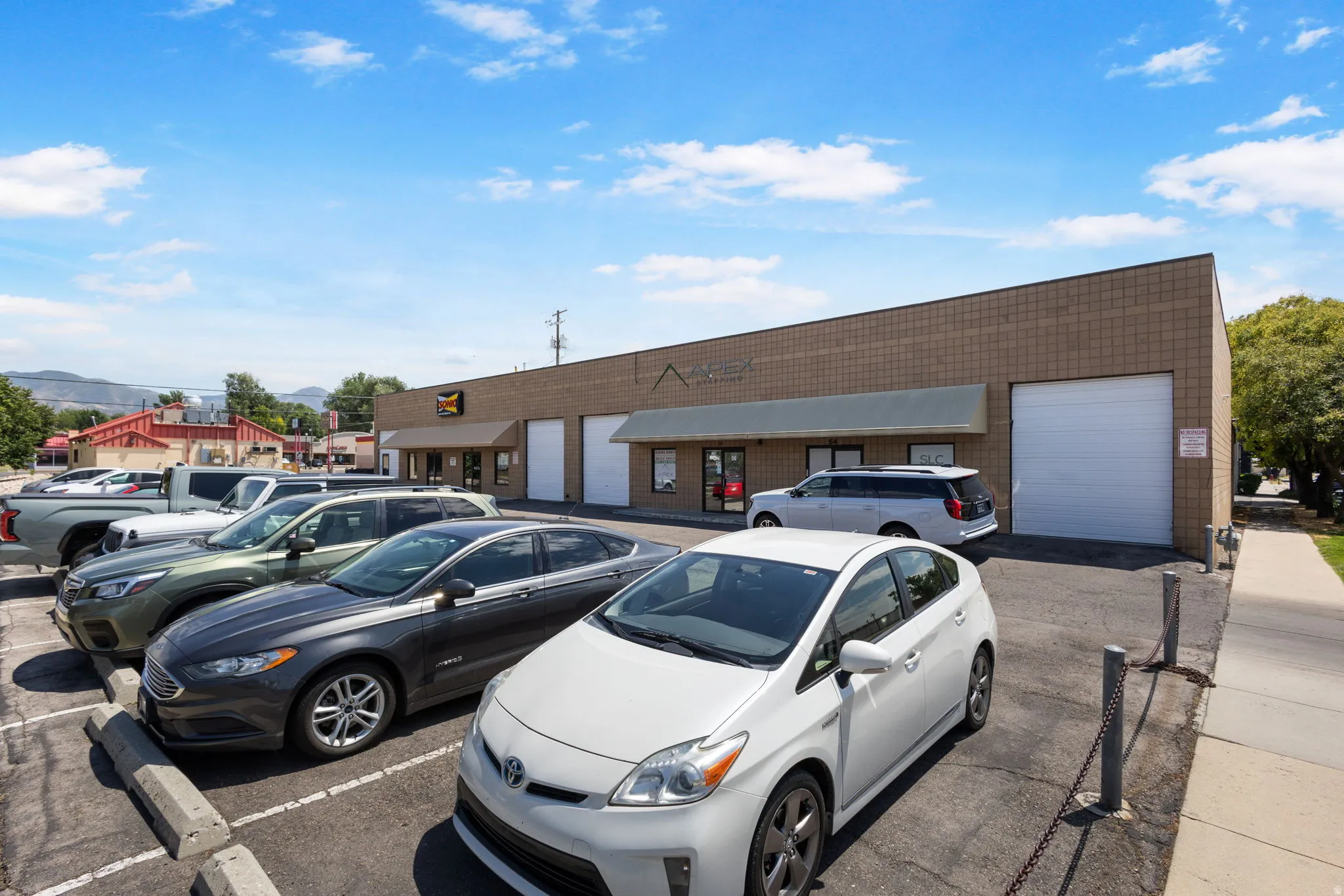 Commercial building featuring a brick facade, multiple garage doors, and dedicated asphalt parking