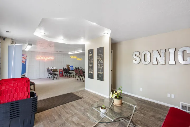 Modern open-concept space featuring a curved soffit ceiling with integrated lighting, polished concrete flooring, and glass partition wall separating the entertaining area