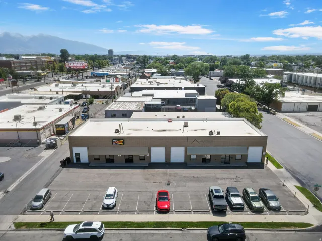 Modern commercial/industrial building featuring a clean, flat roof design with contemporary facade elements, ample front-facing parking with multiple marked spaces, and a functional layout ideal for retail or warehouse operations