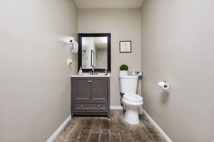 Elegant powder room featuring a dark-stained vanity with dual cabinet doors, white porcelain sink, and brushed nickel faucet