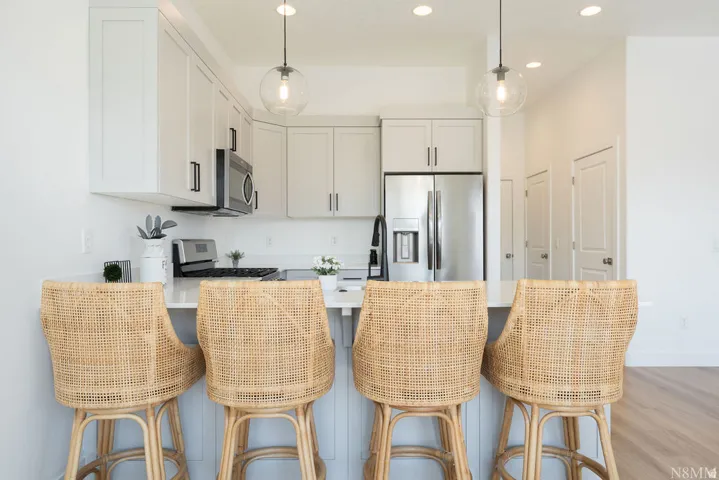 Modern kitchen featuring white cabinetry, stainless steel appliances including a refrigerator with ice and water dispensers, and a gas cooktop