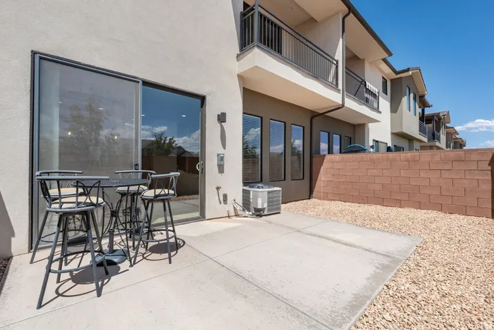 Modern outdoor living space featuring a generous concrete patio with direct access to the residence, complemented by a seated bar-height dining area