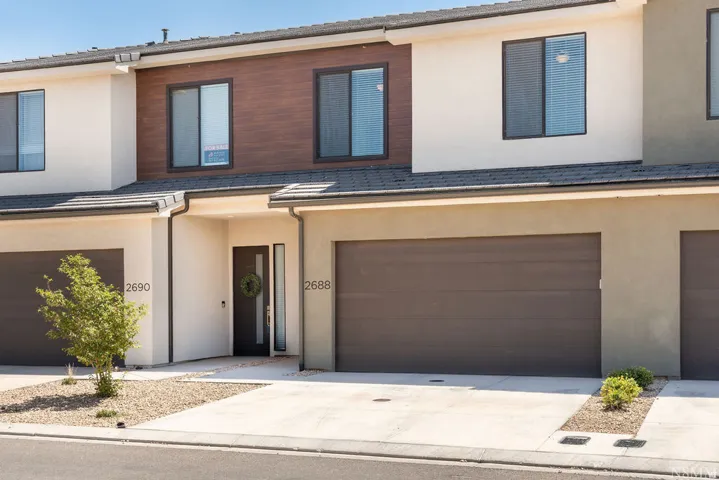 Modern townhome featuring a clean-lined facade with mixed material exterior combining stucco and horizontal wood-finish cladding