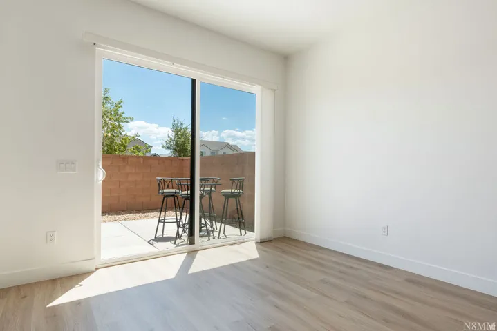 Bright and open living space featuring gleaming wood-finish flooring, clean white walls, and abundant natural light streaming through expansive sliding glass doors