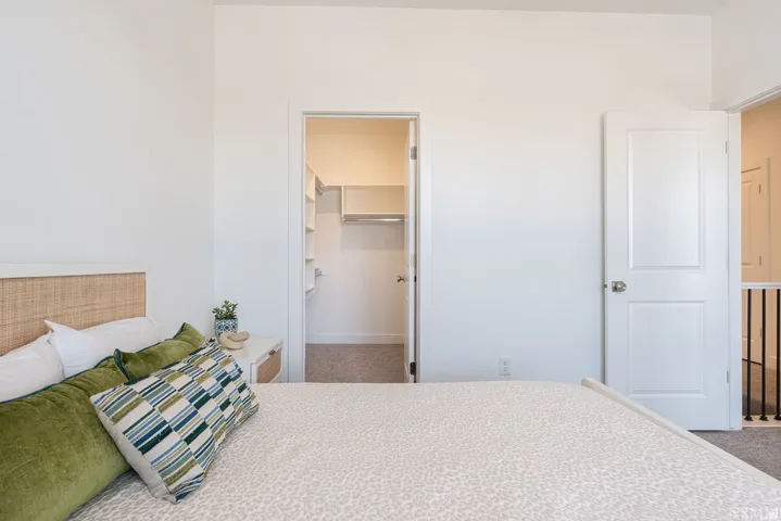 Spacious primary bedroom featuring a wood-finish headboard, neutral carpet flooring, and abundant natural light