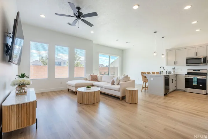 Open-concept living and kitchen space featuring wood-finish flooring throughout, recessed ceiling lighting, and a ceiling fan