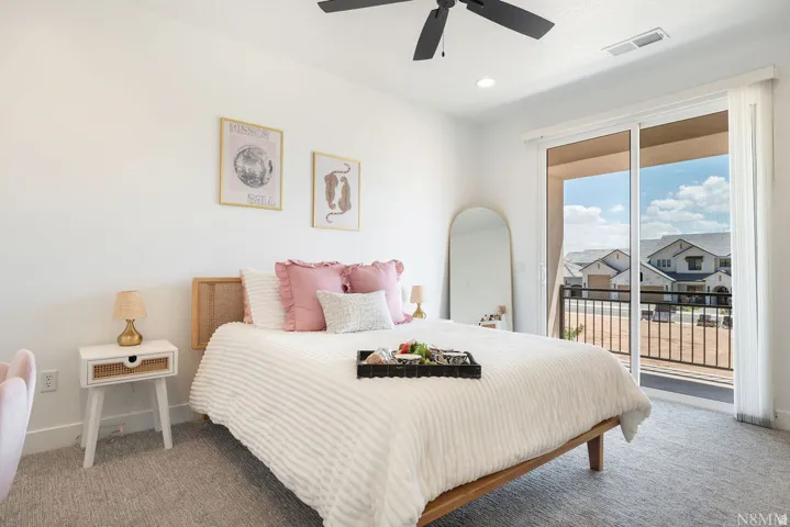 Bright secondary bedroom showcasing a wood-frame bed, neutral striped bedding, and soft pink accent pillows