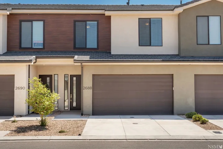 Modern townhome featuring a clean-lined façade with mixed material finishes including wood-tone cladding and stucco exterior