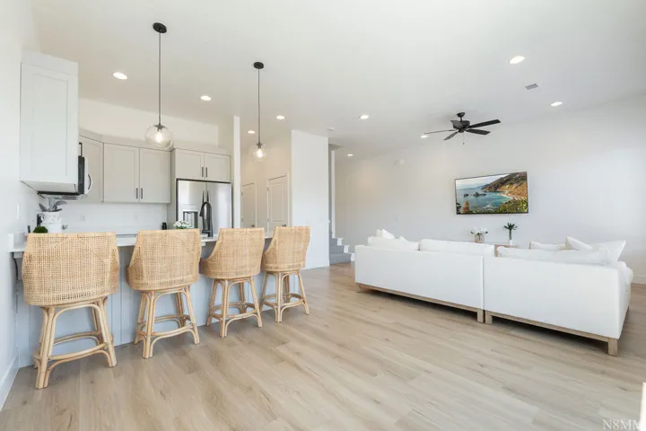 Open-concept living space featuring a fully equipped kitchen with white cabinetry, stainless steel appliances, and a large island with seating for four