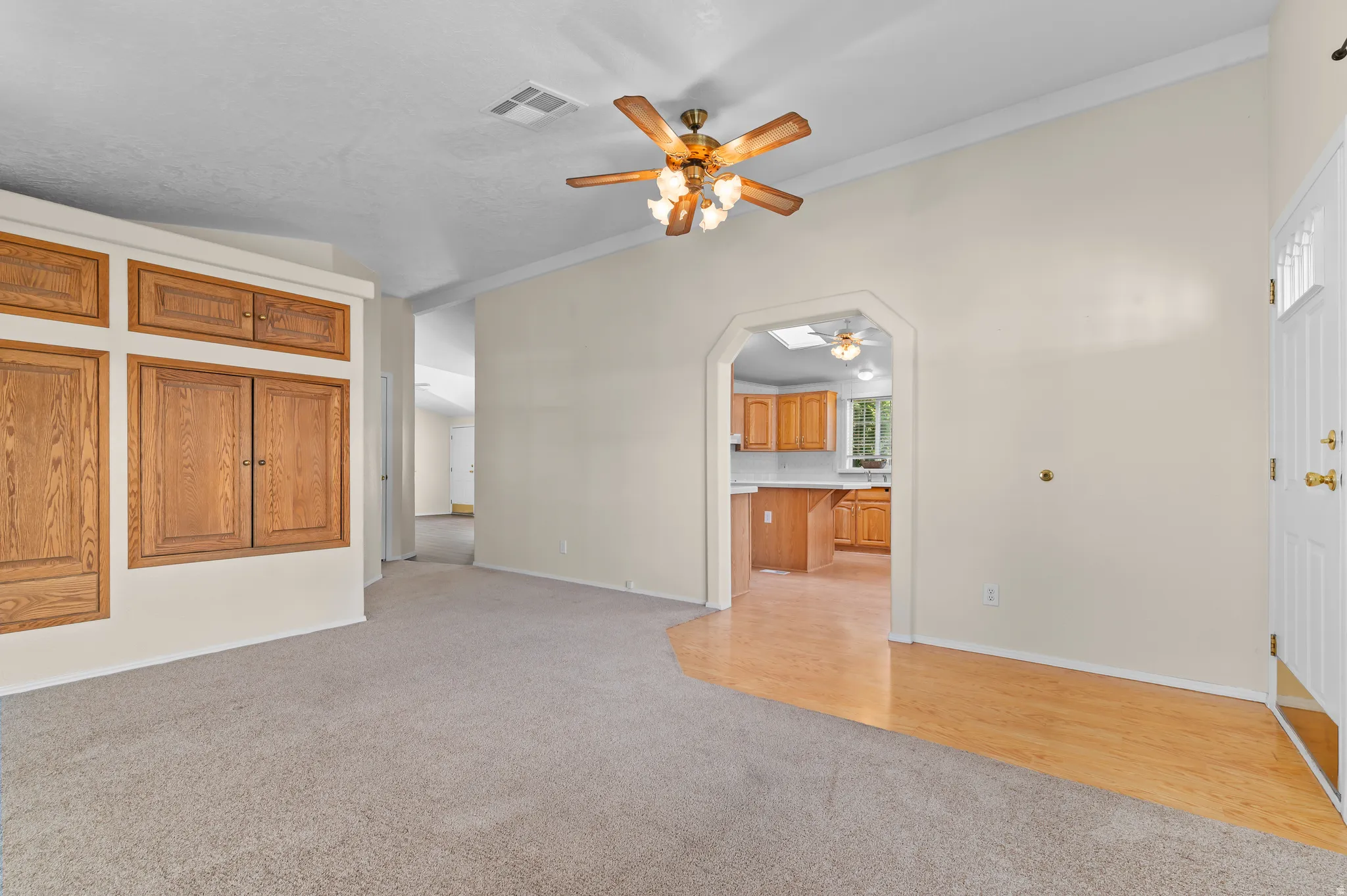 Living area featuring a vaulted ceiling with a ceiling fan, recessed lighting, and a blend of carpet and wood-finish flooring.