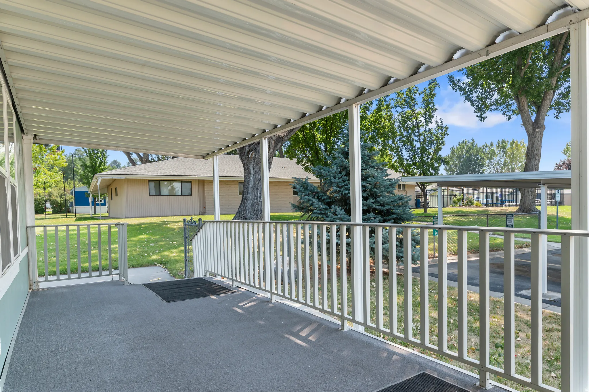 Covered porch with white metal railings and corrugated metal roof overhang, offering shaded outdoor living space