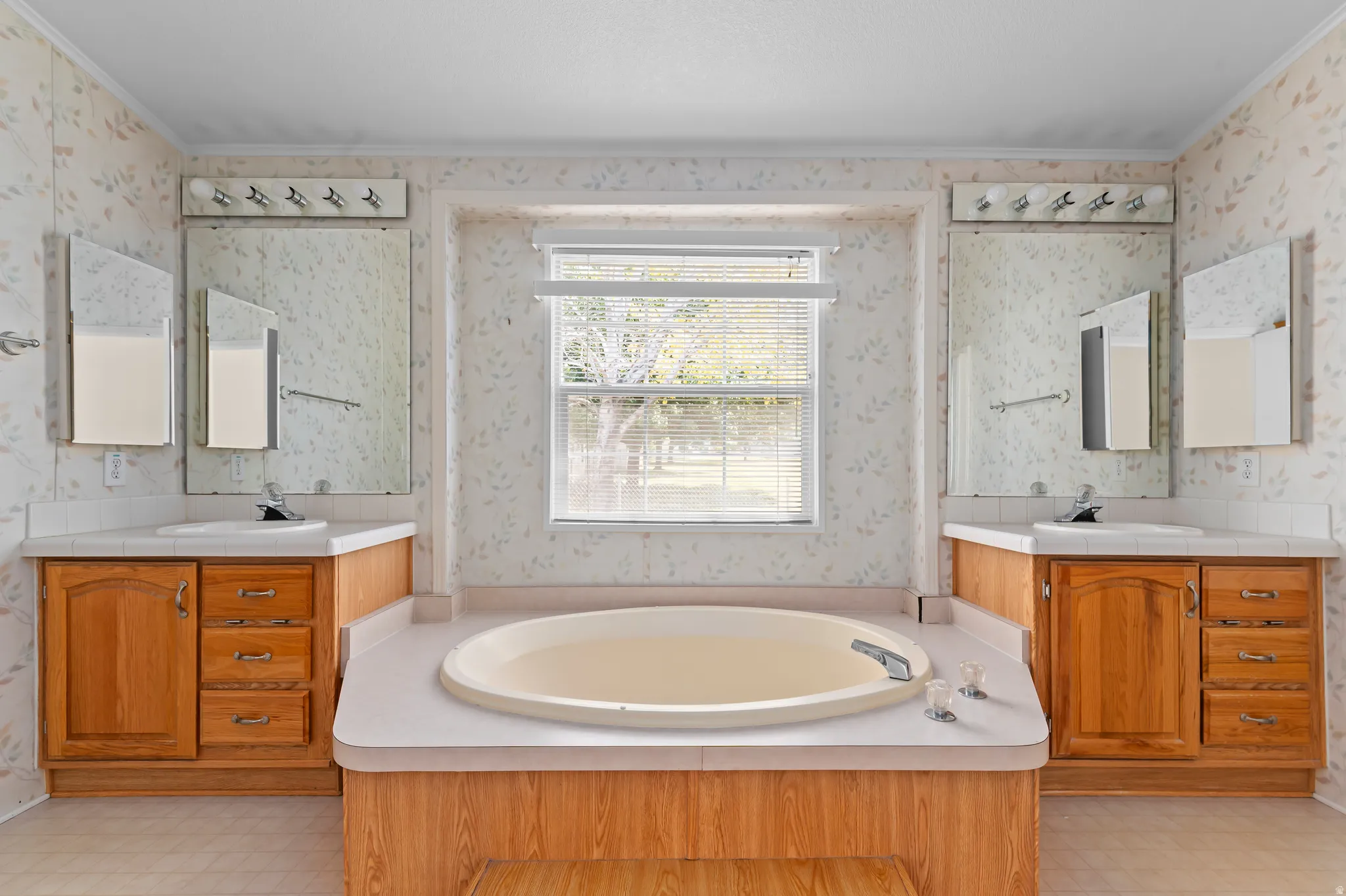 Spa-inspired primary bathroom featuring dual vanities with warm wood cabinetry, marble countertops, and polished nickel fixtures
