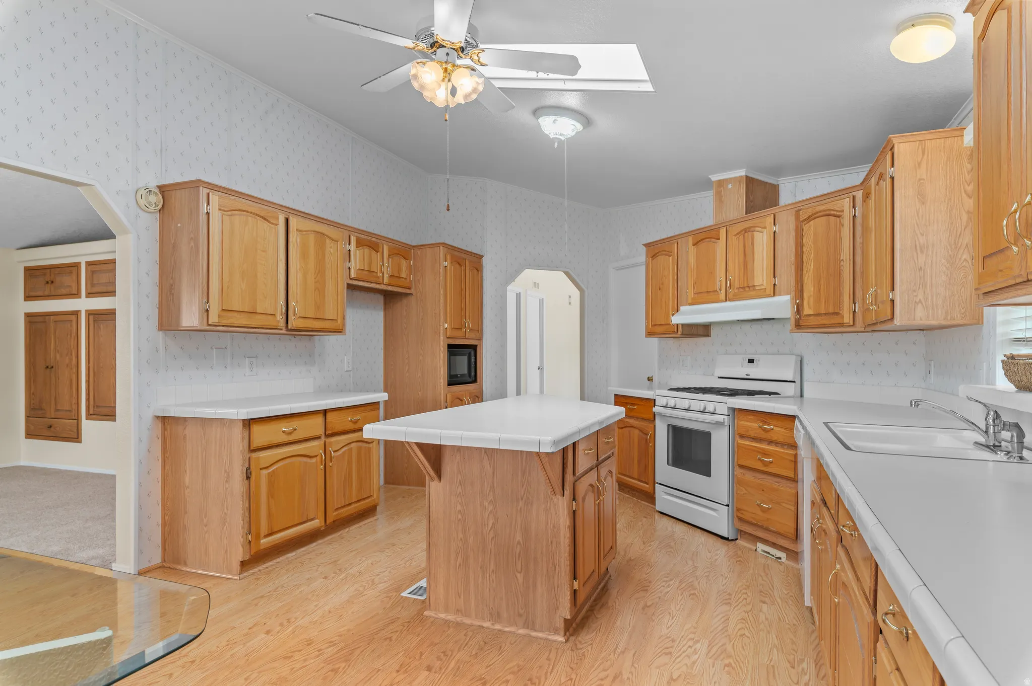 Spacious kitchen featuring extensive wood cabinetry, light-toned countertops, and wood-finish flooring.