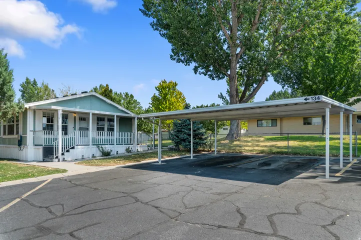 Exterior residence featuring a covered front porch with white railings, a light green facade, and a dedicated two-car carport
