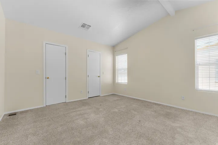 Spacious room featuring vaulted ceilings, light-colored walls, and neutral carpeting