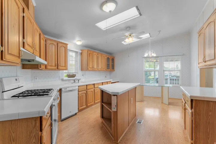 Full kitchen featuring wood-finish cabinetry, white tile countertops, and a central island.