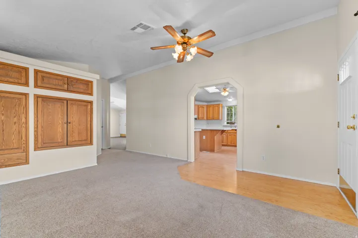 Living area featuring a vaulted ceiling with a ceiling fan, recessed lighting, and a blend of carpet and wood-finish flooring.