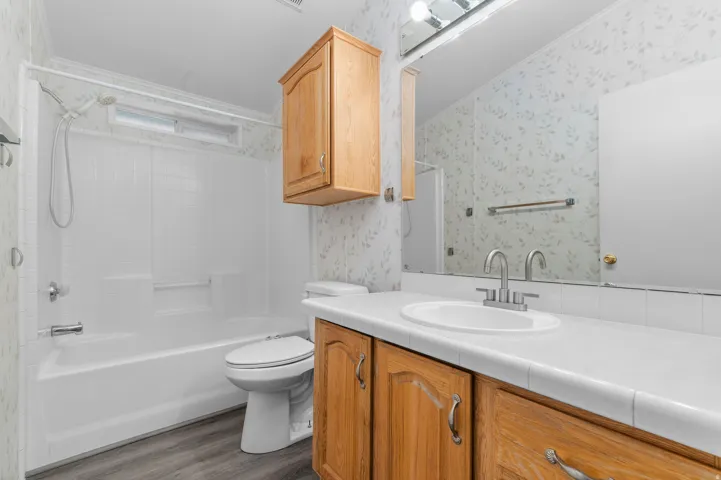Bathroom featuring wood-finish cabinetry, white countertop, and an integrated sink with a chrome faucet.