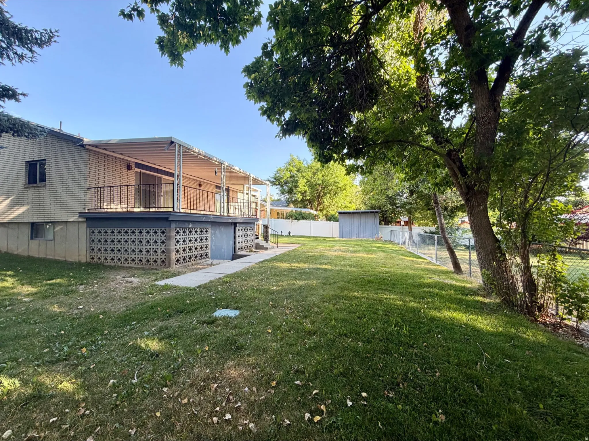 Back yard featuring established trees and a paved walkway