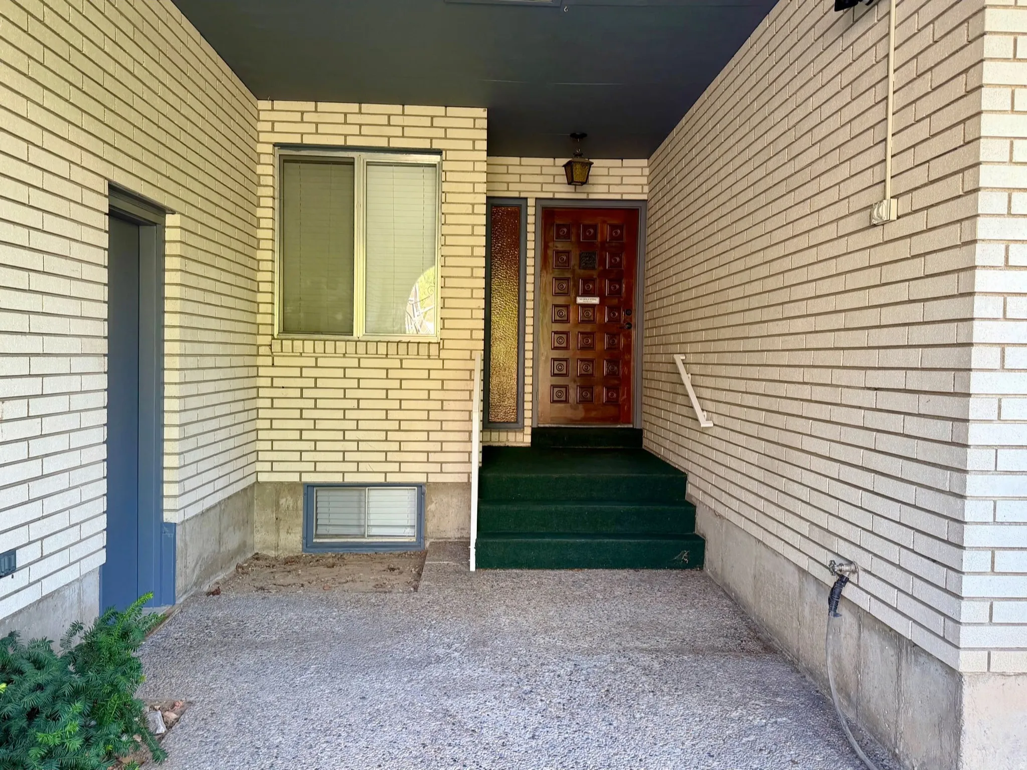 Entryway featuring a decorative wood door, transom window, and white brick veneer