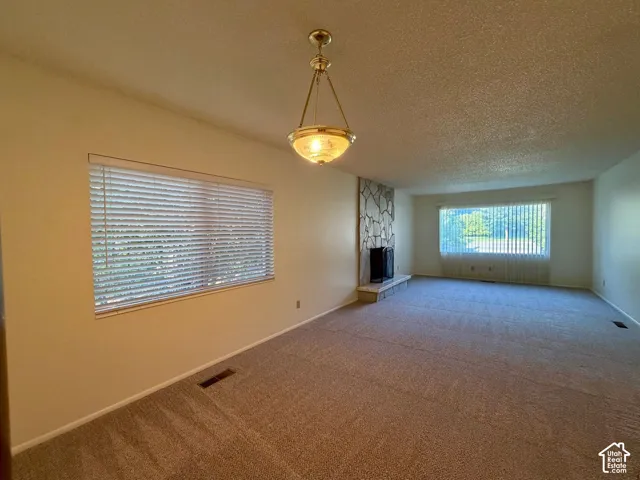 Spacious living filled with natural light with a stone fireplace adjacent to the dining room
