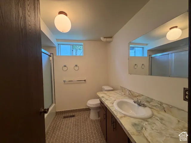 Bright bathroom featuring recessed and wall-mounted lighting, dual windows with natural light, patterned tile accent wall, and white ceramic fixtures including pedestal sink and bathtub with surround