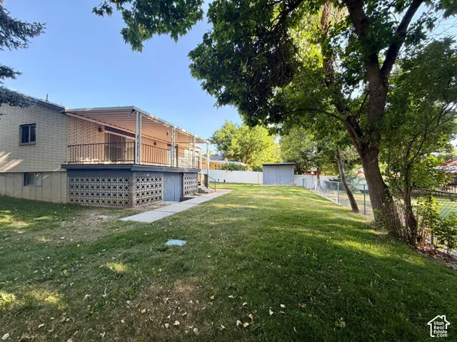 Back yard featuring established trees and a paved walkway