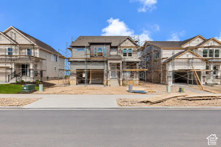 Two-story residential exterior featuring stone veneer accents, multi-pane windows, a gabled roofline, and an attached multi-car garage