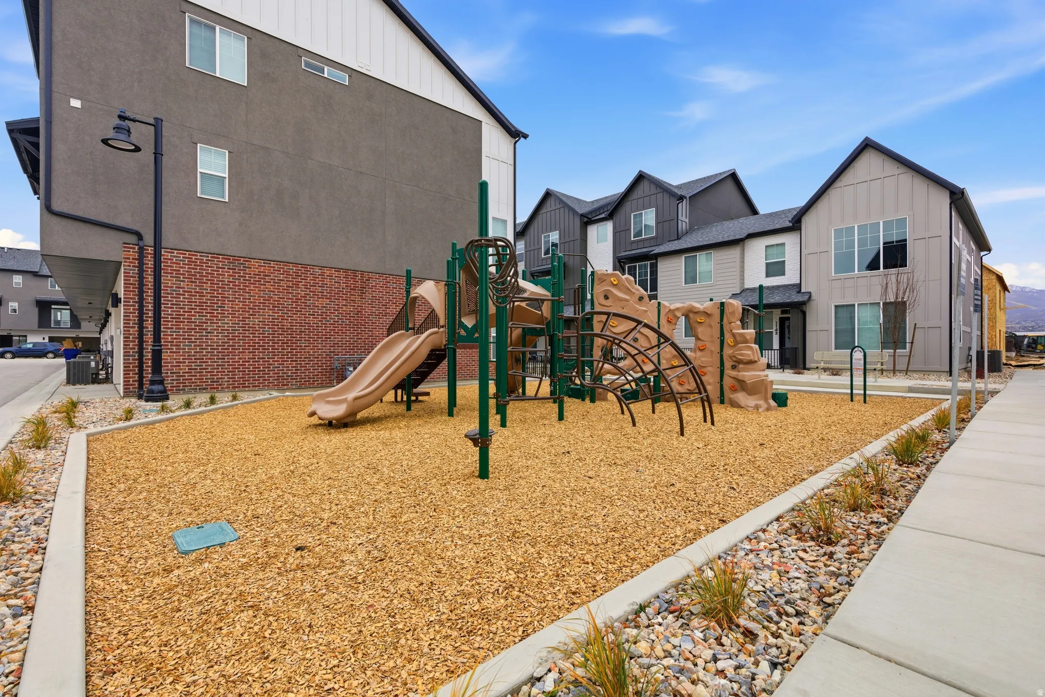 Community playground featuring a climbing structure, slide, and wood chip surfacing